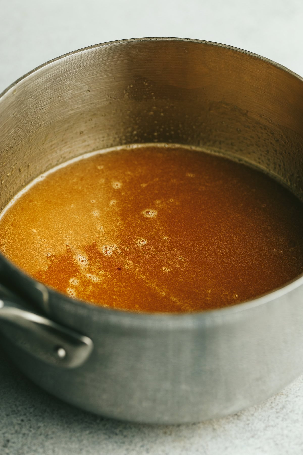 Caramel sauce in a stainless steel saucepan for keto pecan pie.