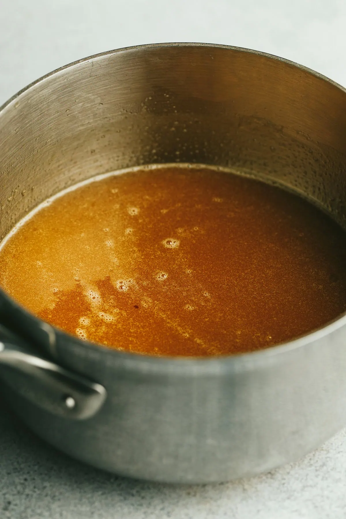 Caramel sauce in a stainless steel saucepan for keto pecan pie.