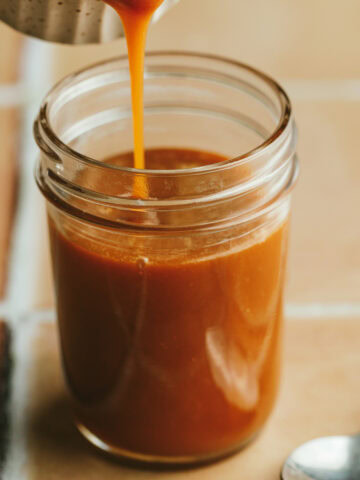 Keto caramel sauce being poured into a glass jar.