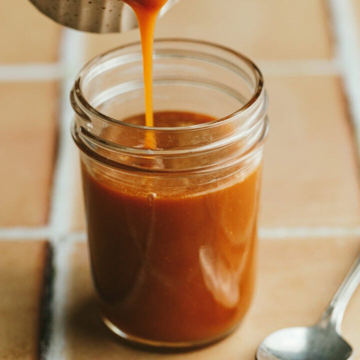 Keto caramel sauce being poured into a glass jar.
