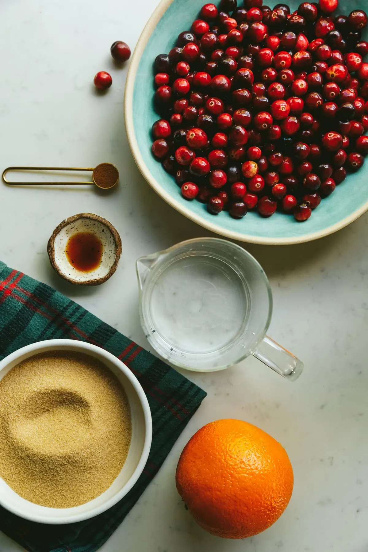 Ingredients for sugar-free cranberry sauce on a white marble counter.