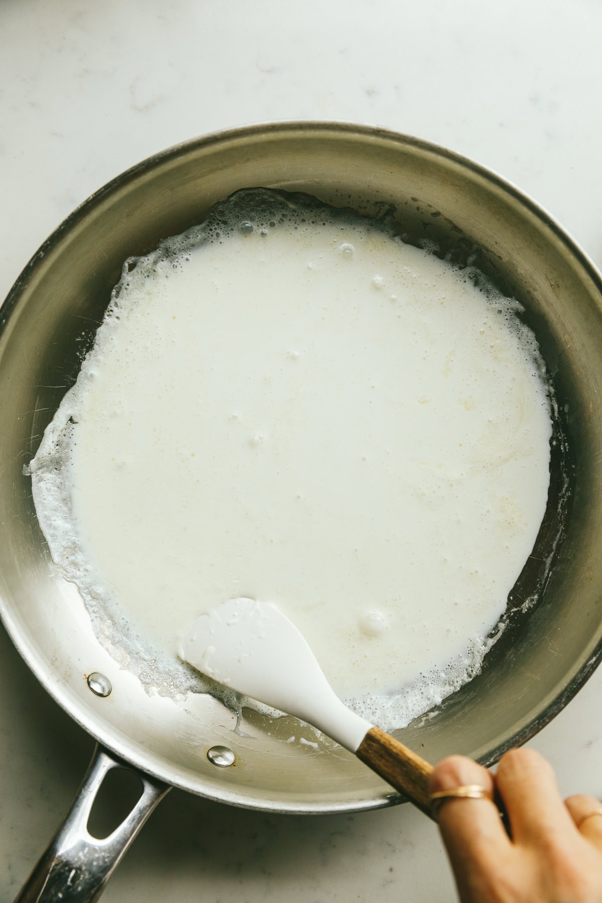 Stirring cream in a pan with a spatula for cream fried eggs.