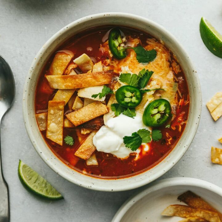 A bowl of keto chicken tortilla soup with sour cream, jalapeños, and melted cheese.