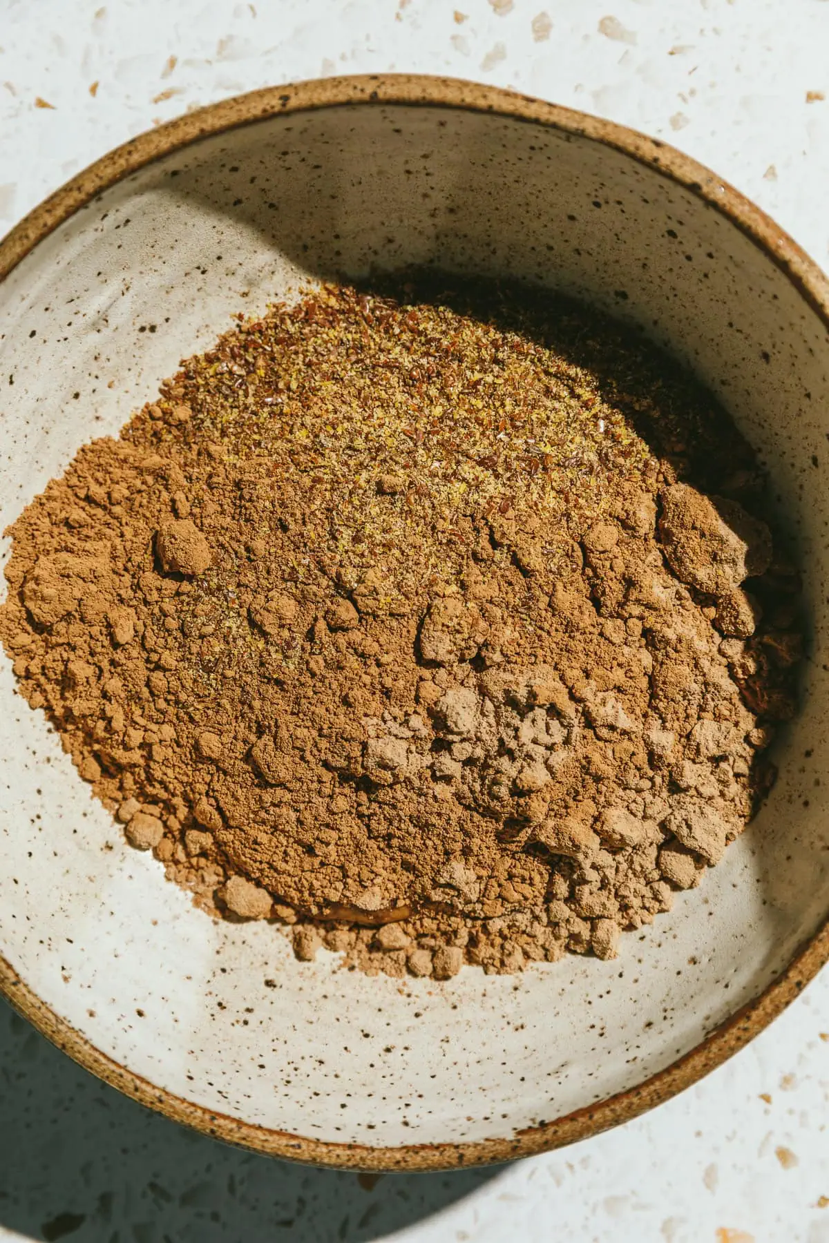 Dry ingredients for protein brownie bites in a speckled mixing bowl.