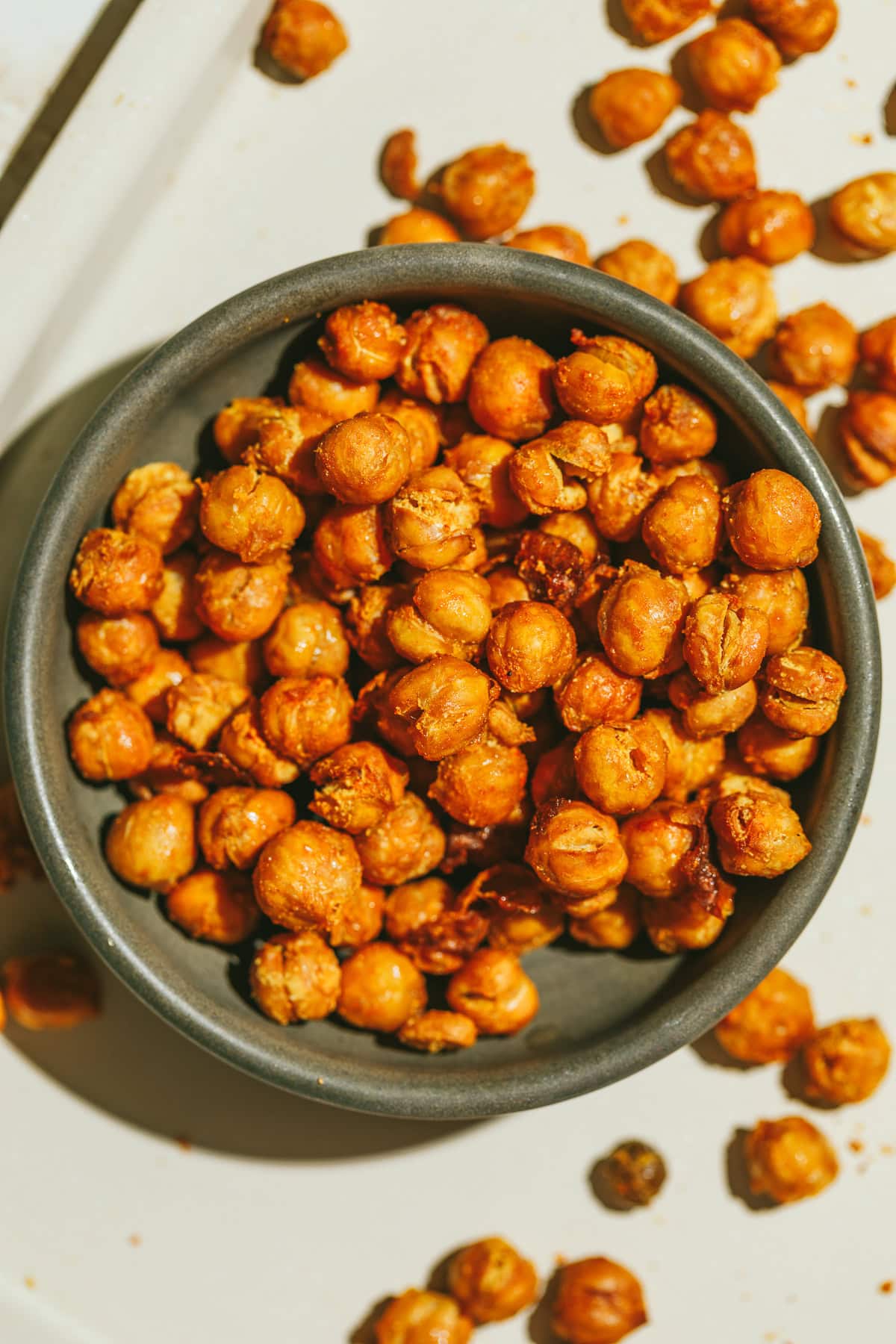 Crispy air fryer chickpeas in a brown bowl on a pan.