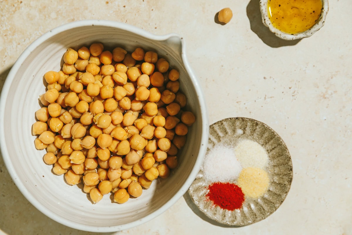 Ingredients for air fryer chickpeas on a beige marble surface.