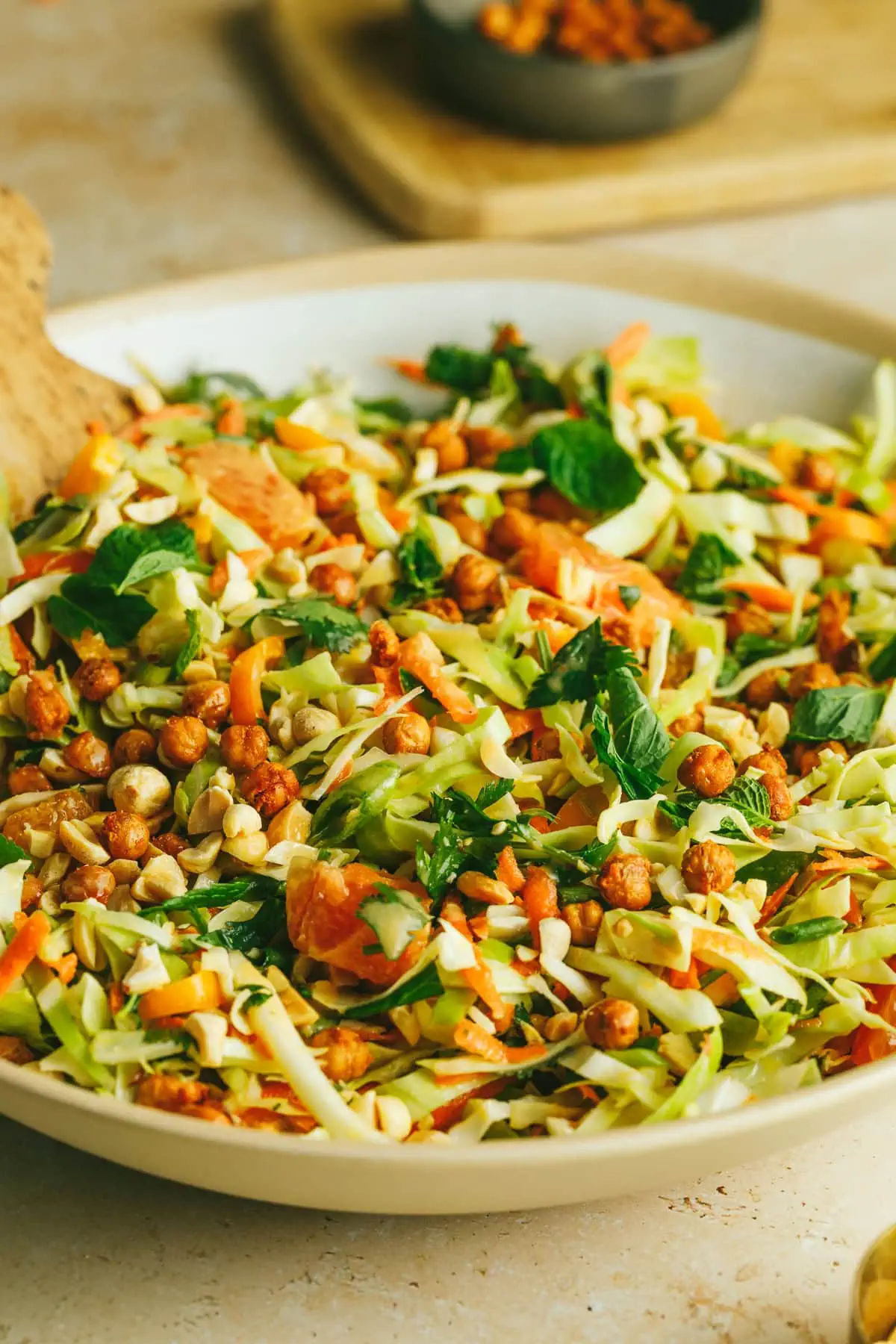 Cabbage crunch salad in a serving bowl with wooden serving utensils.