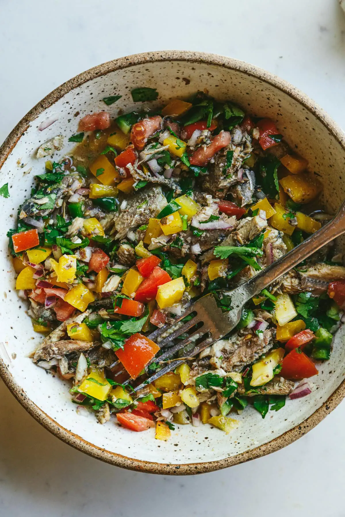 Mixed sardine escabeche in a white speckled serving bowl.