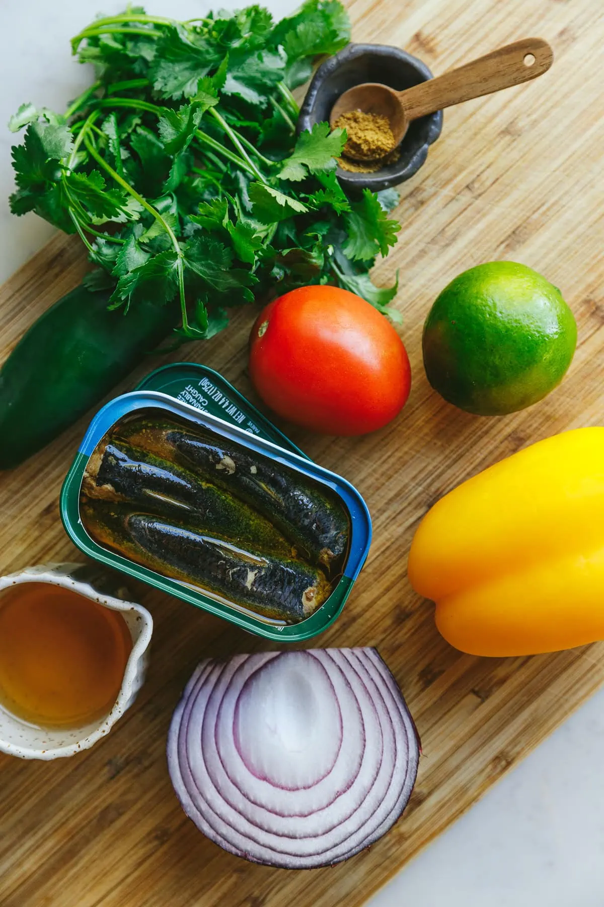 Ingredients on a cutting board for sardine escabeche recipe.