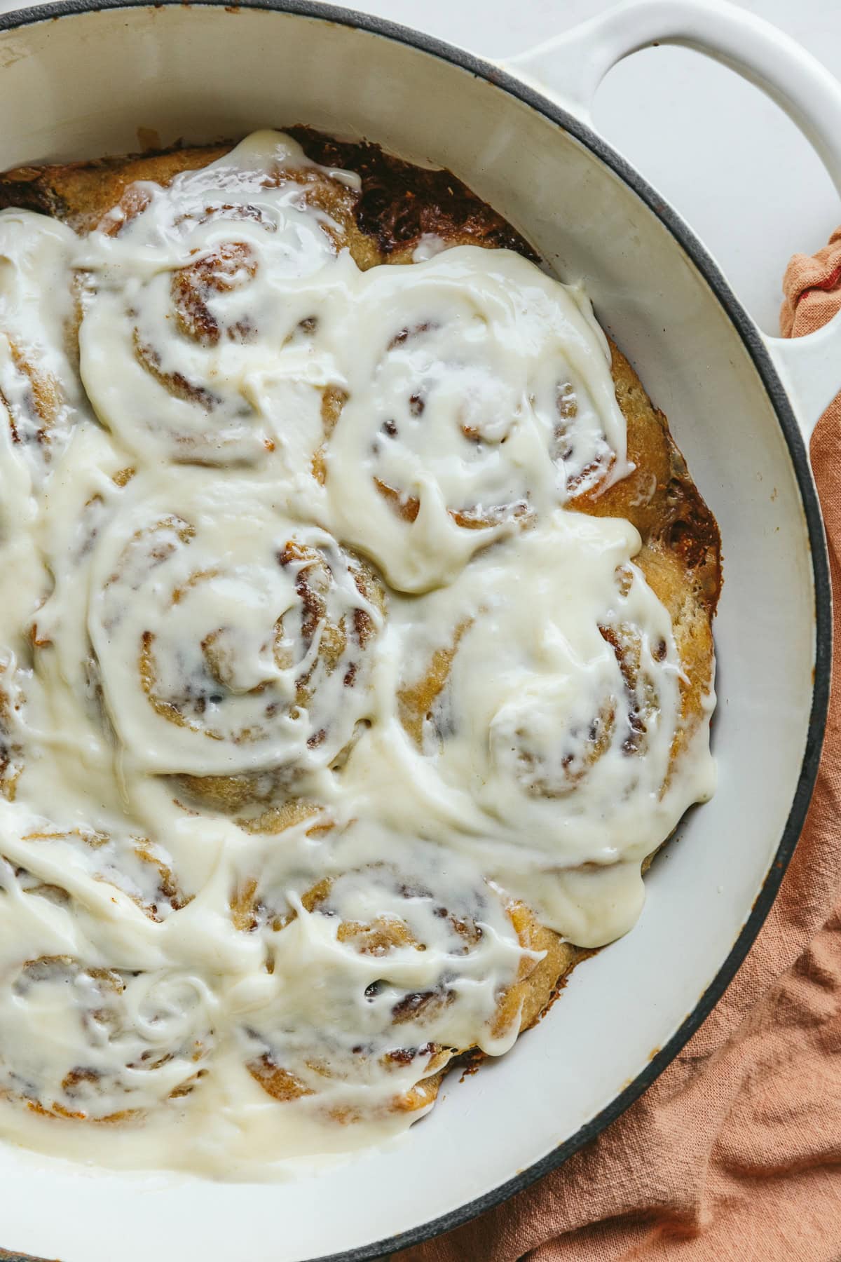Keto cinnamon rolls with cream cheese frosting in a white baking dish.