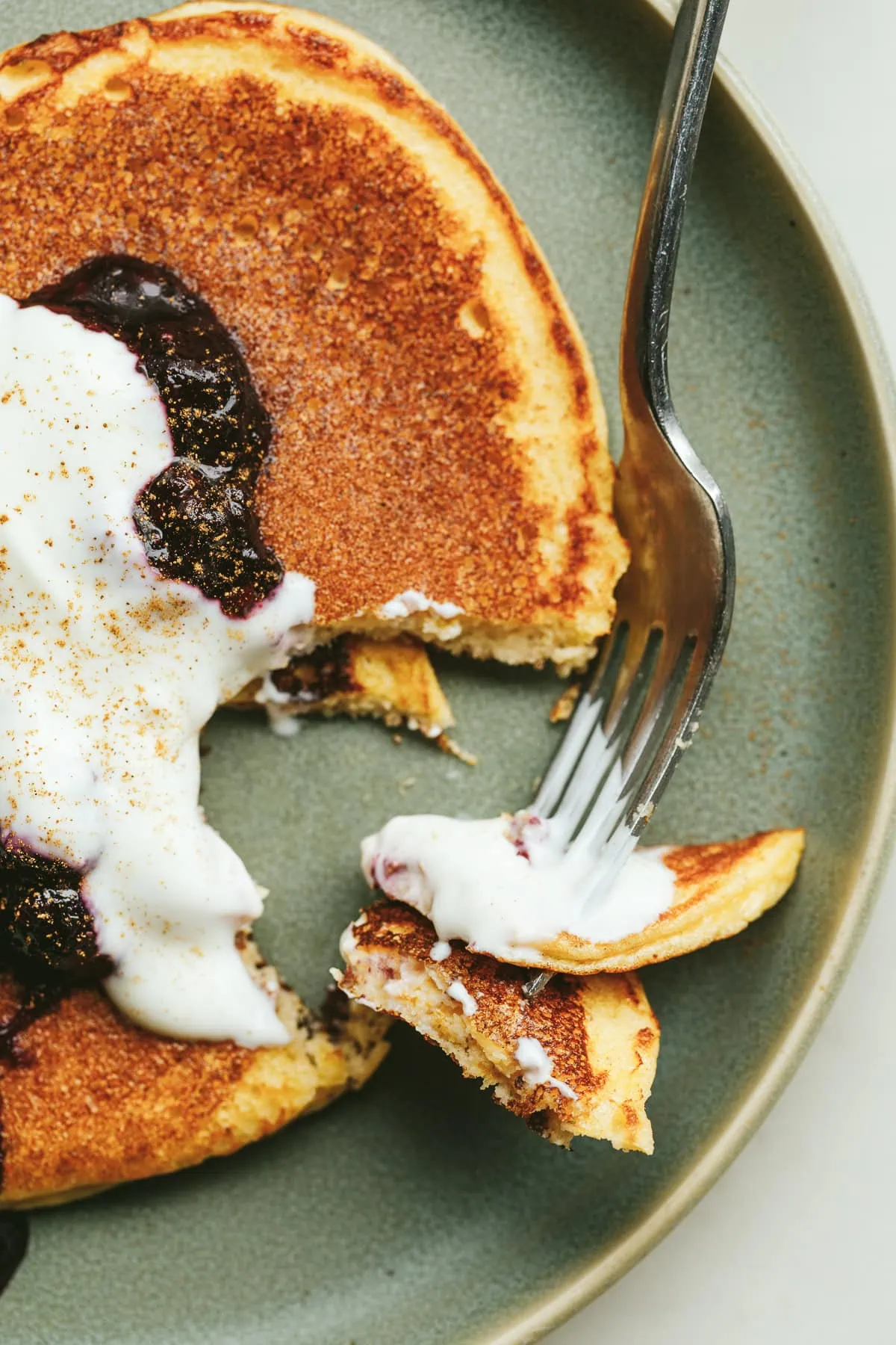 Closeup of a bite of cottage cheese pancakes with berry and yogurt.