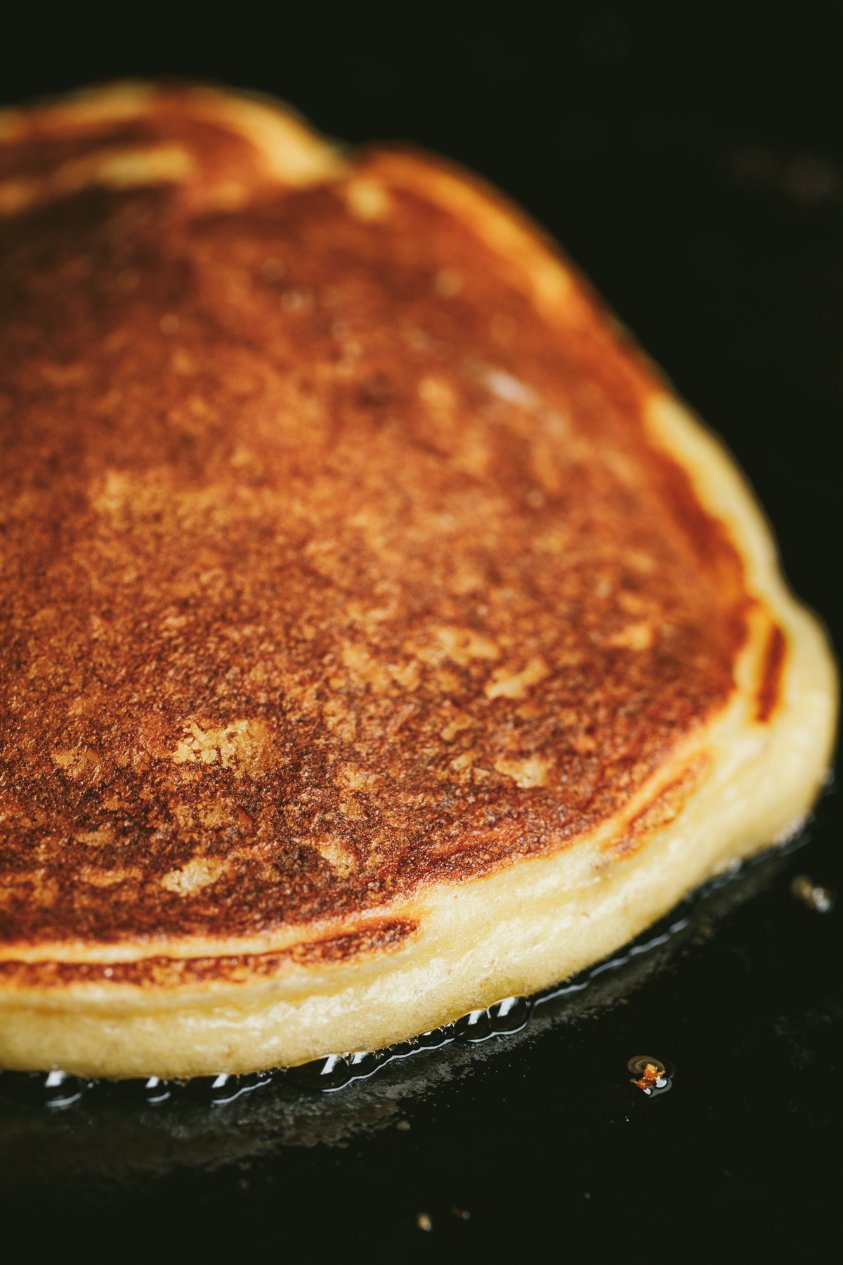 Closeup of a keto cottage cheese pancake cooking in a black skillet.