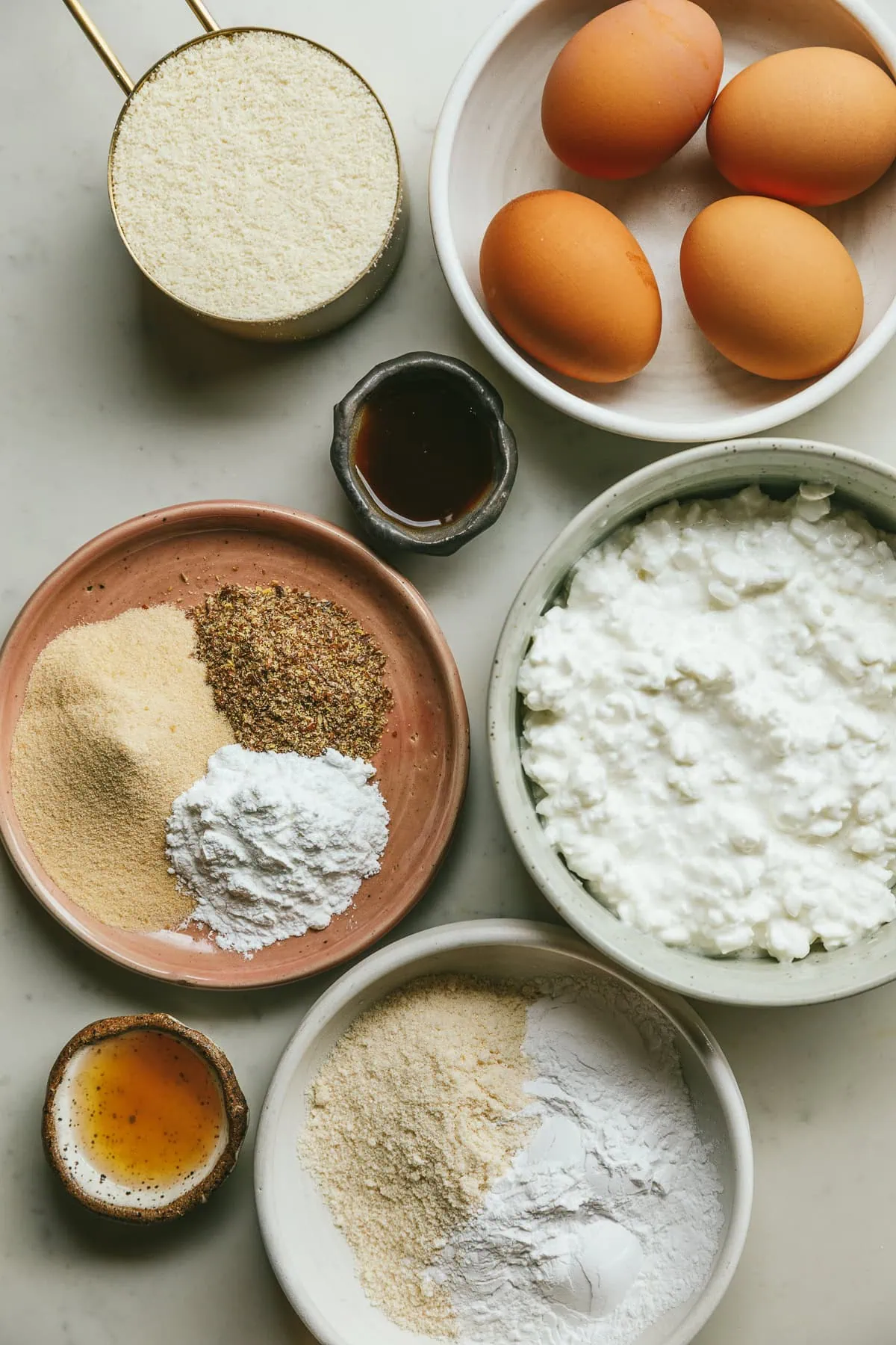 Ingredients for cottage cheese pancakes on a white marble countertop.
