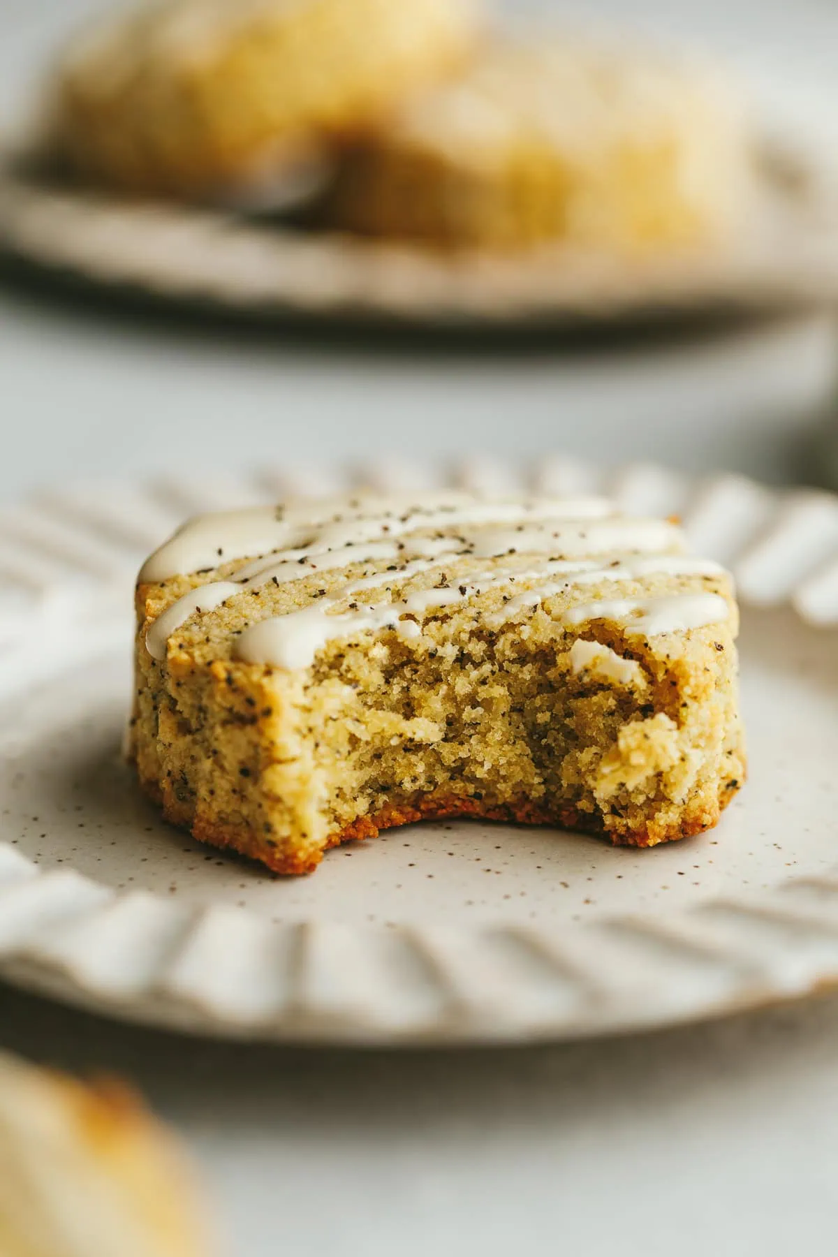 A closeup shot of a bite taken out of an earl grey scone on a plate.
