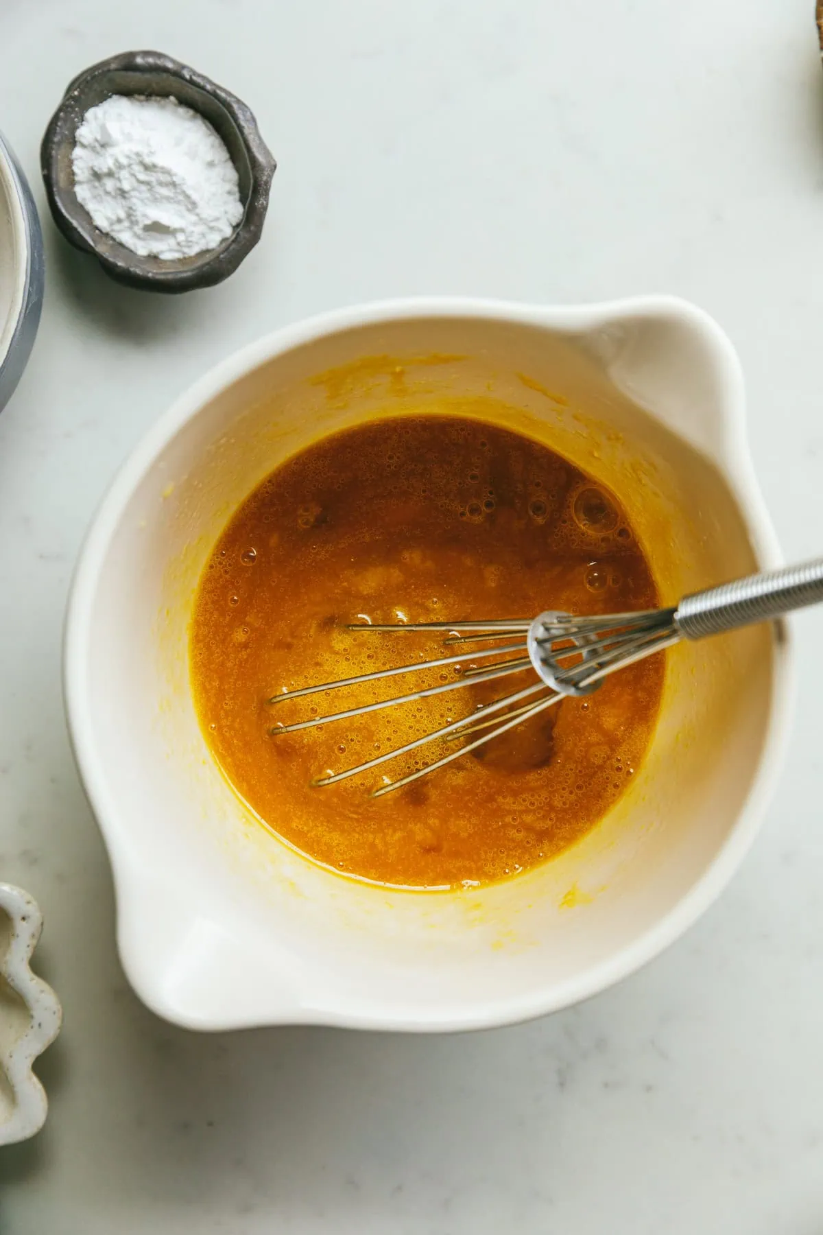 Wet ingredients for keto pinwheels with a whisk in a mixing bowl.