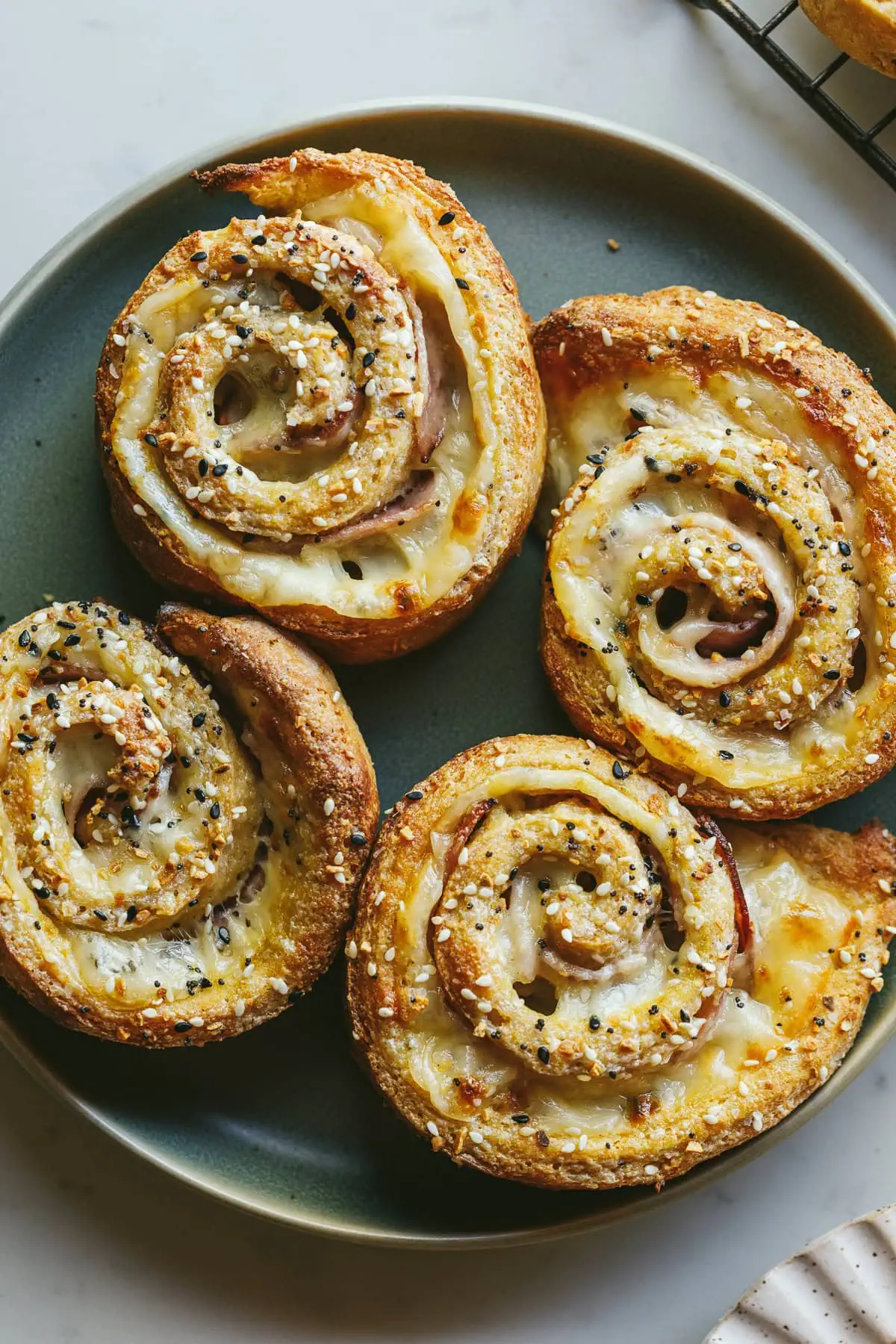 Four keto pinwheels with ham and swiss on a green plate.