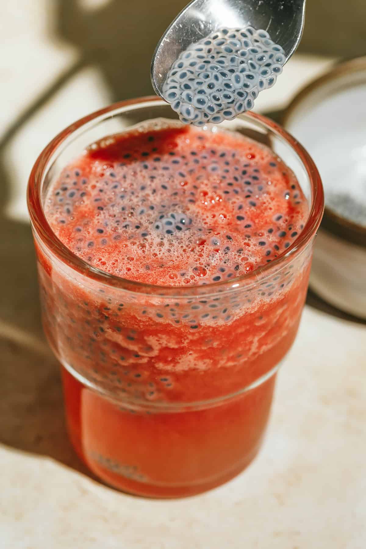 Spooning soaked basil seeds into a watermelon slushie.