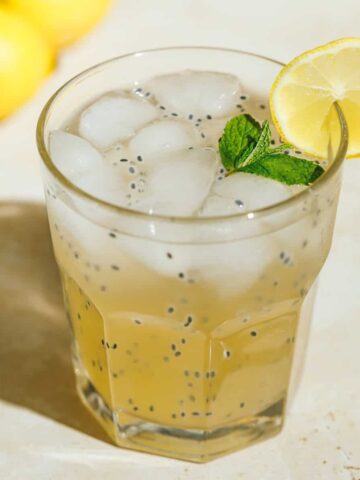 Iced green tea lemonade basil seed drink with garnishes in a glass.
