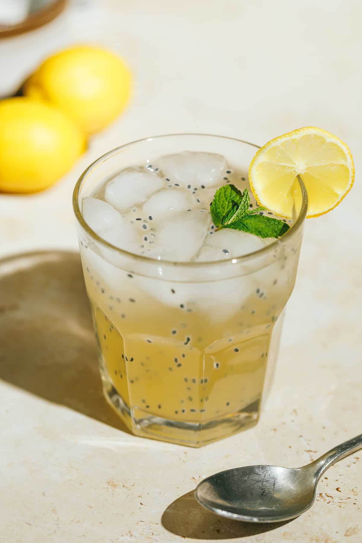 Iced green tea lemonade with basil seeds with a lemon slice garnish and mint.