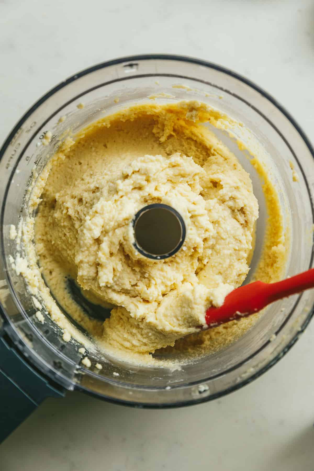 Keto cottage cheese pizza crust dough in a food processor with a red spatula.