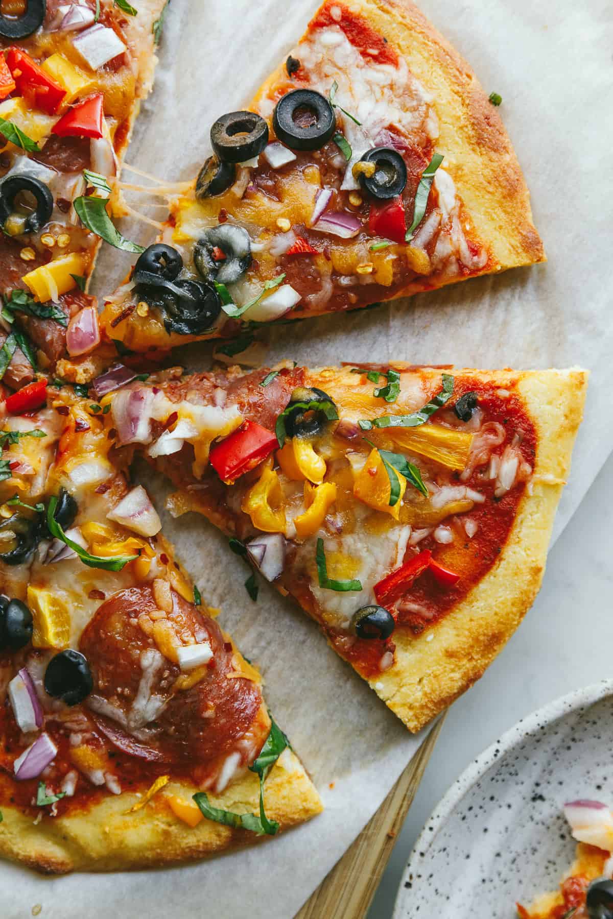 Slices of a baked keto cottage cheese pizza with pizza toppings.