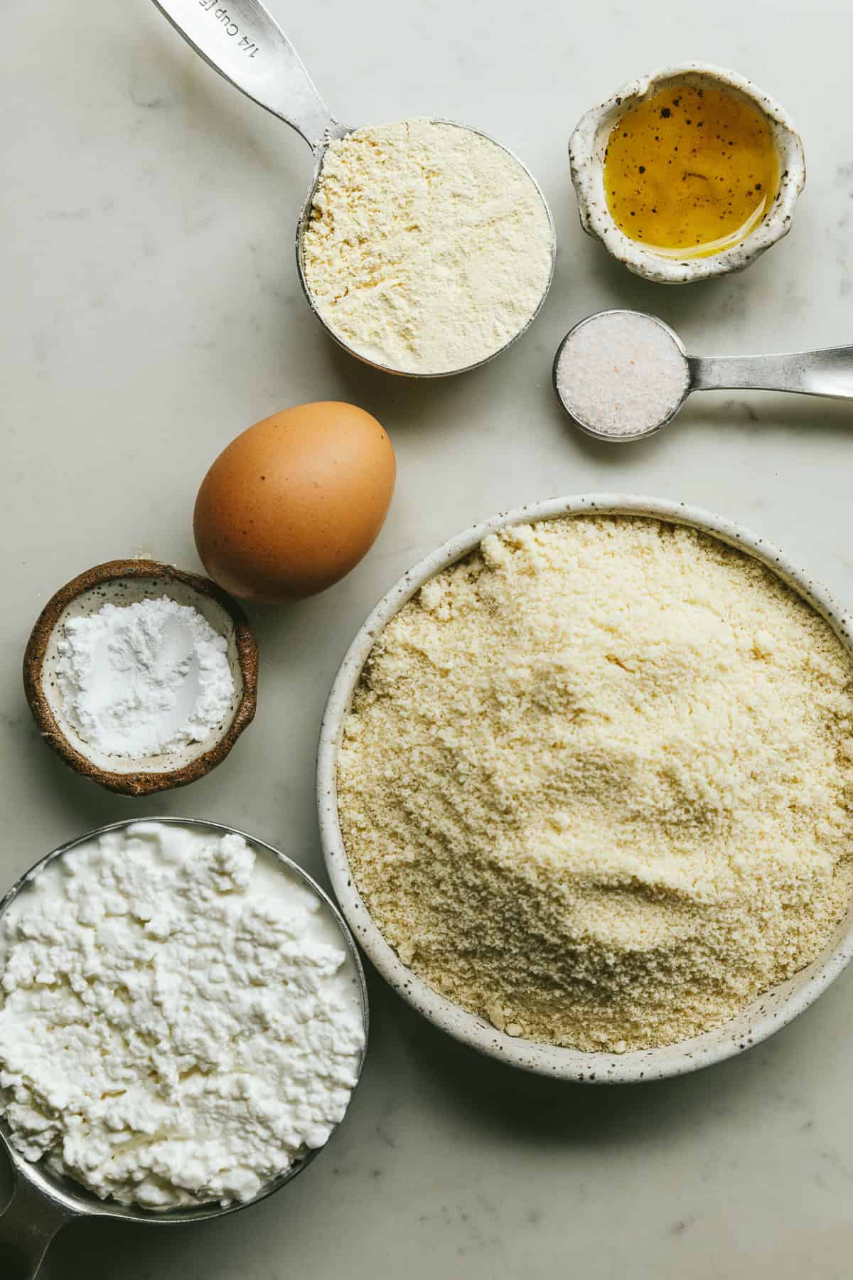 Ingredients for keto cottage cheese pizza crust on a white marble countertop.