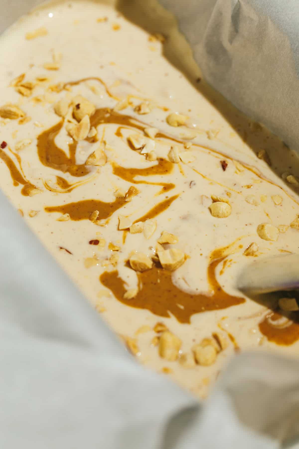 Swirls of peanut butter and peanuts in keto peanut butter ice cream before freezing.