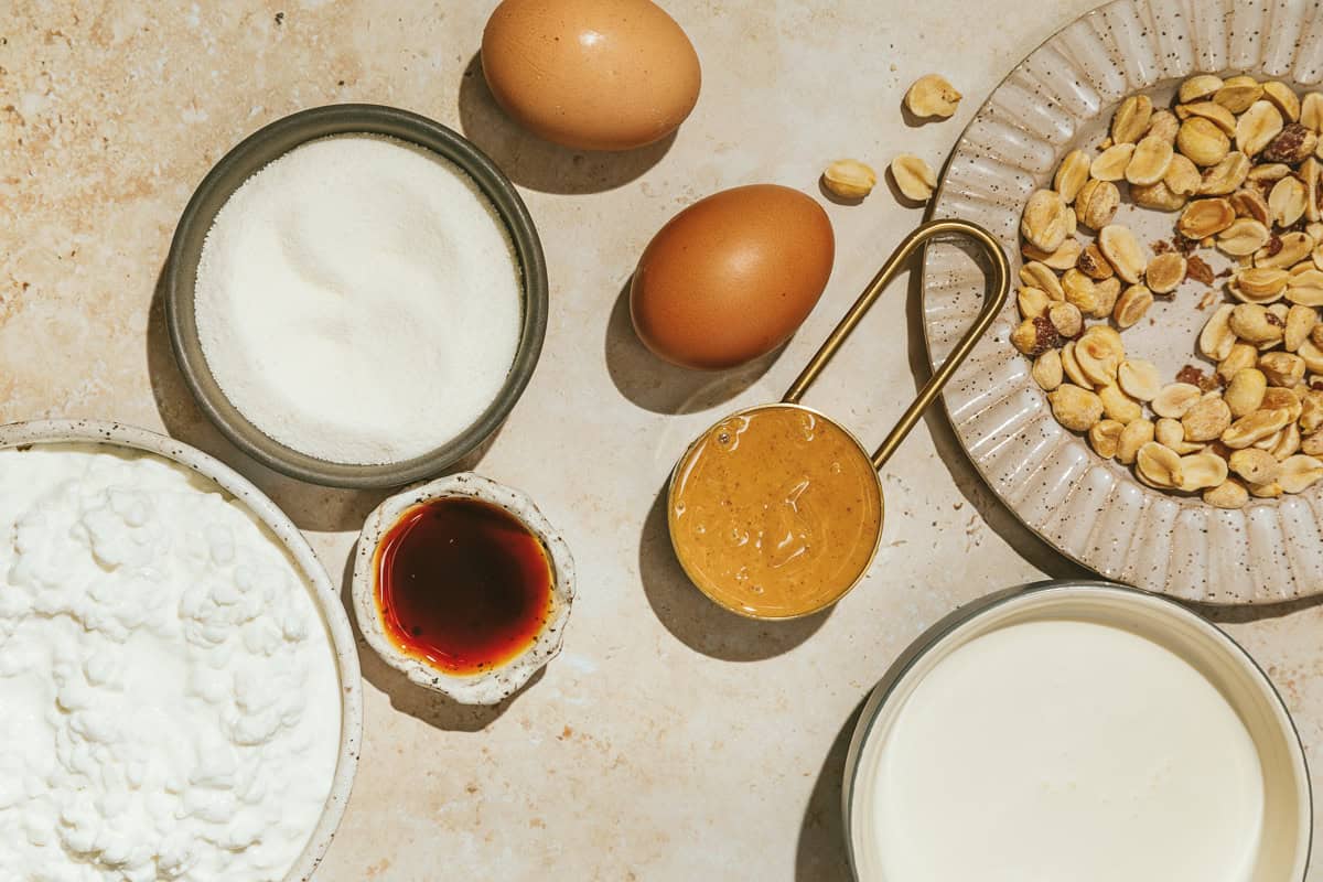 Ingredients for keto peanut butter ice cream arranged on a beige surface.