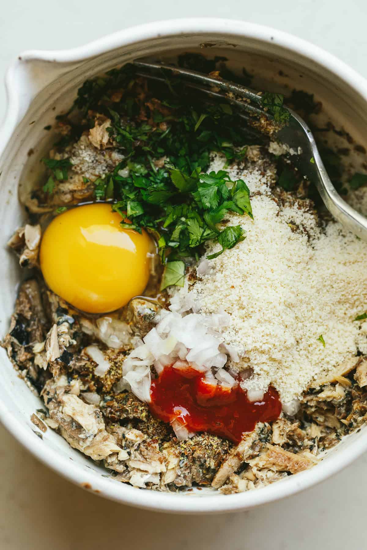 Sardine cake ingredients combined in a white bowl.