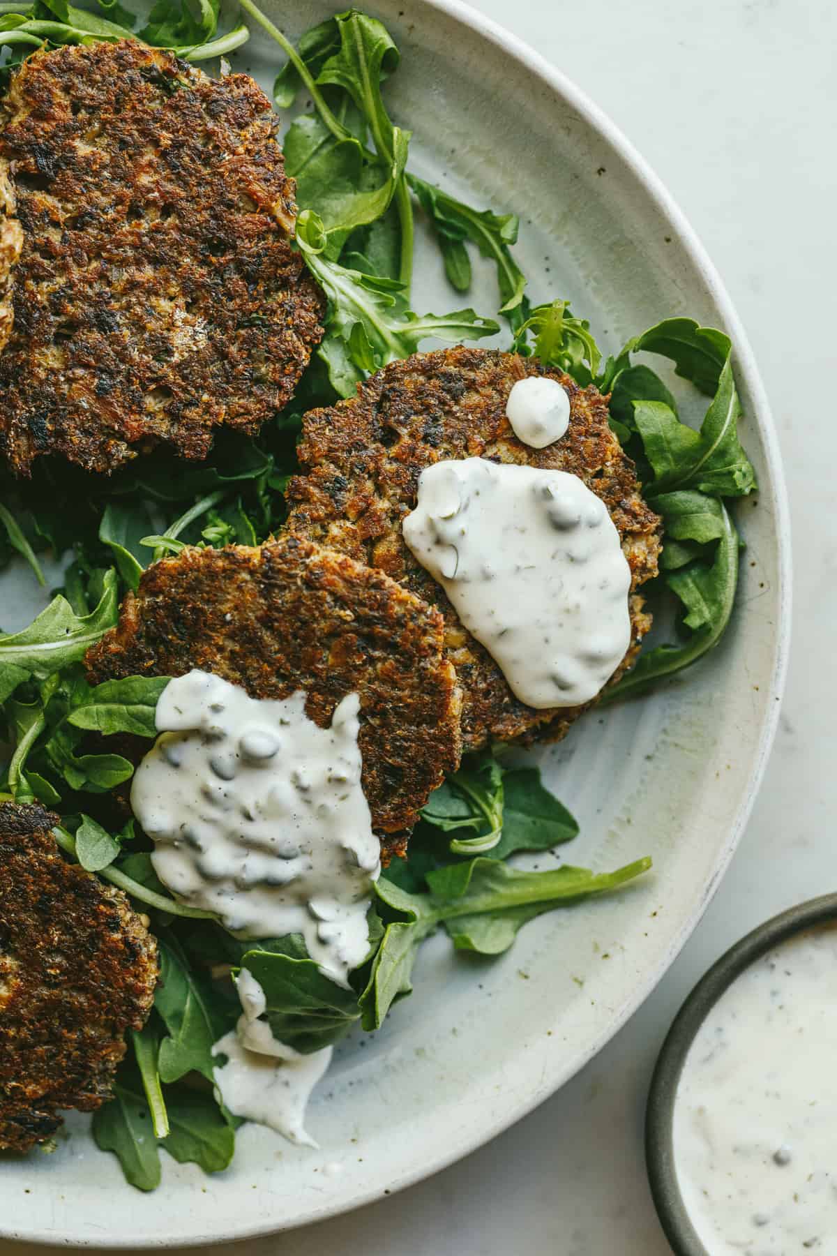 Sardine cakes on a bed of arugula with aioli on top.