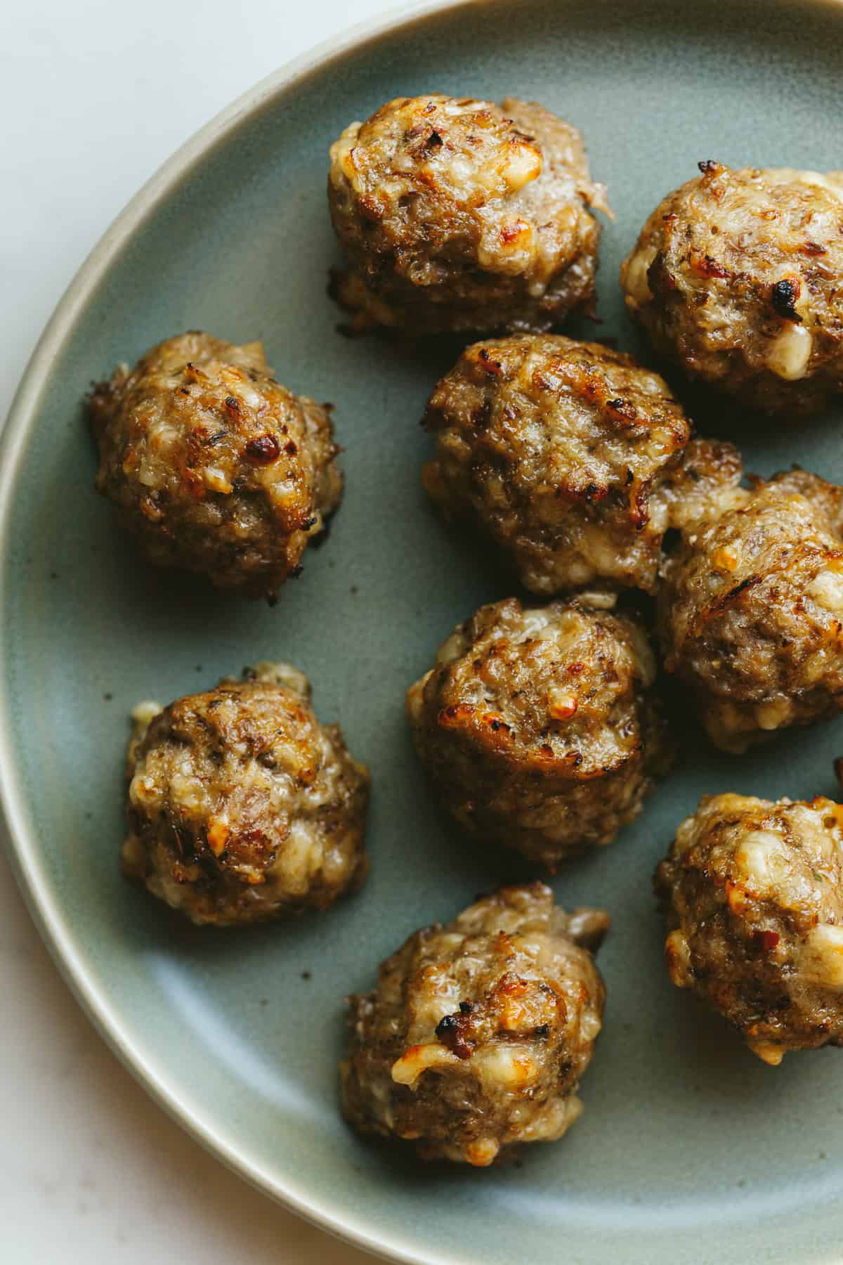 Breakfast meatballs on a green serving plate.