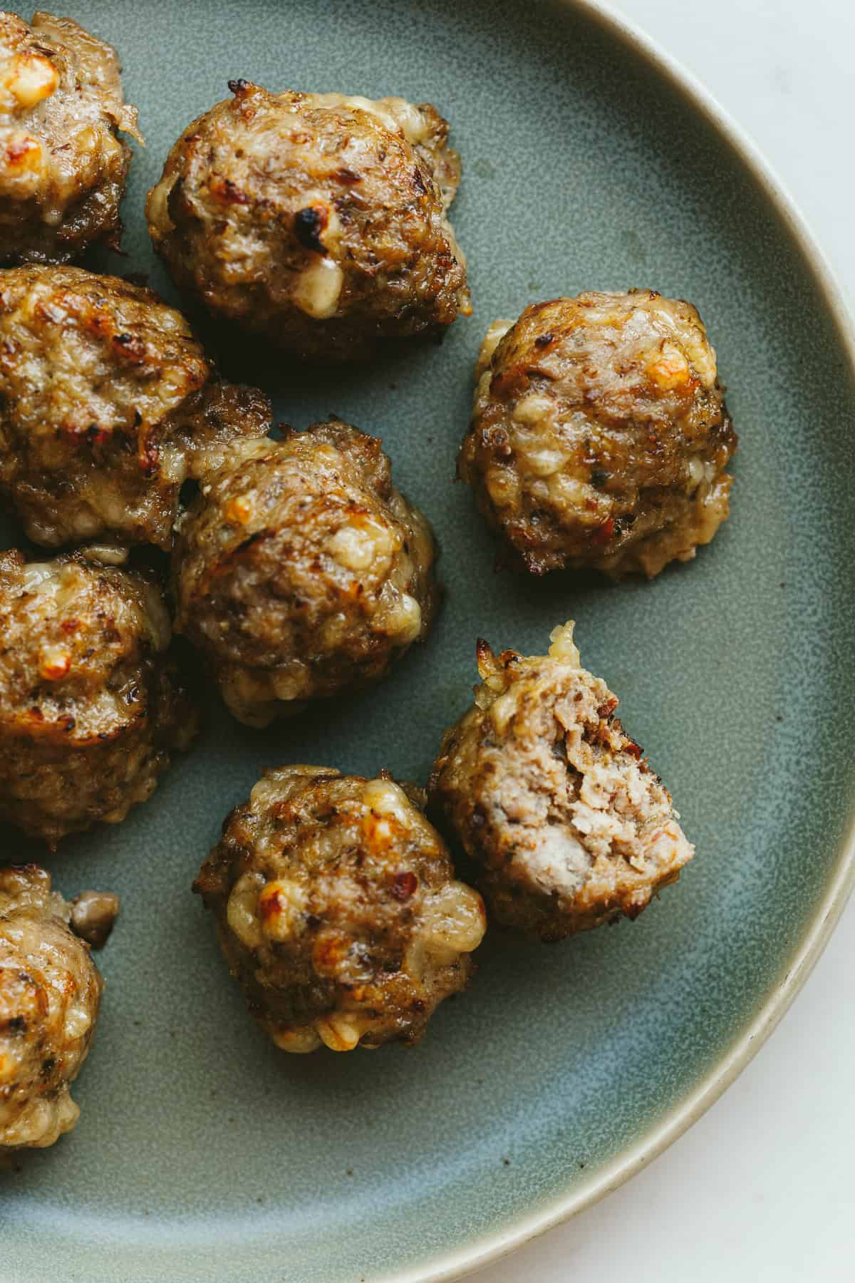 Several breakfast meatballs on a green plate.