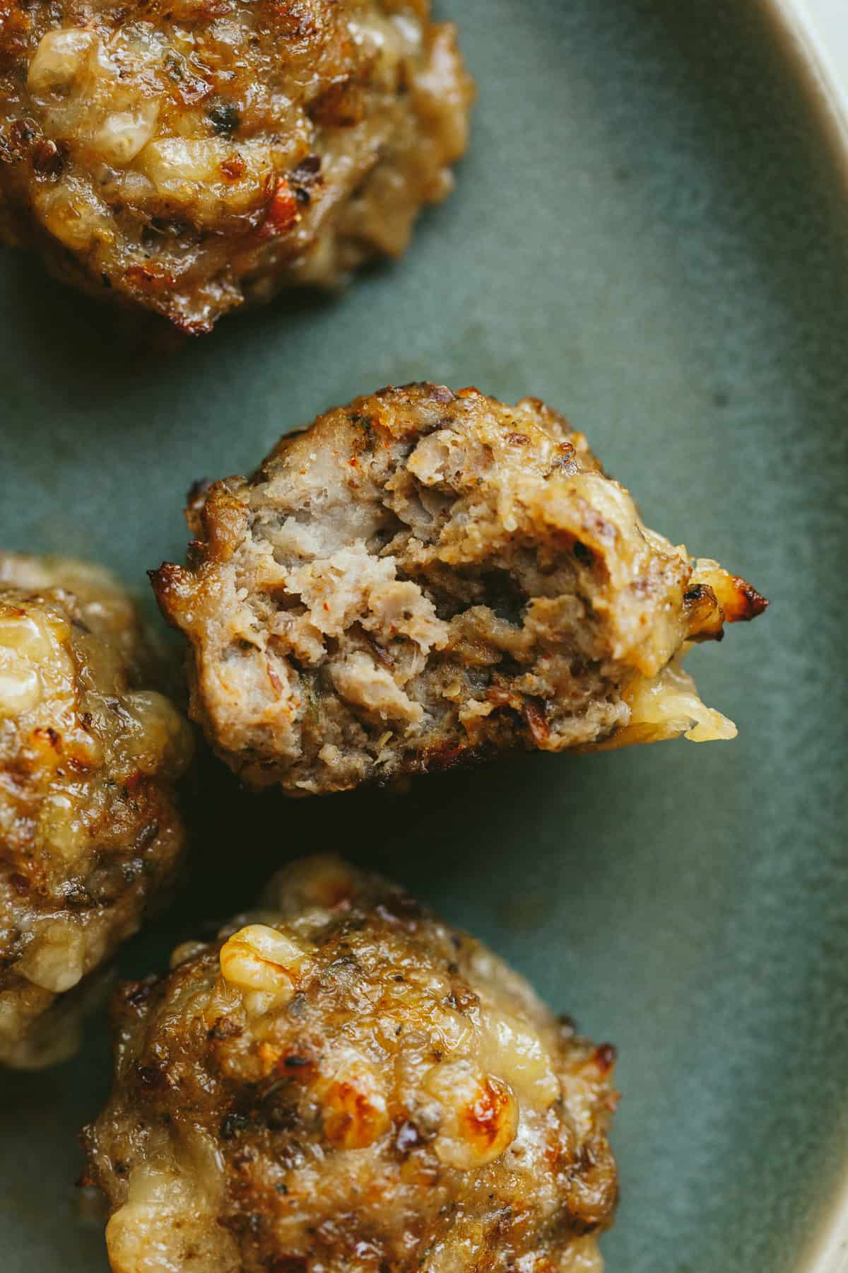 A closeup of a breakfast meatball on a green plate.