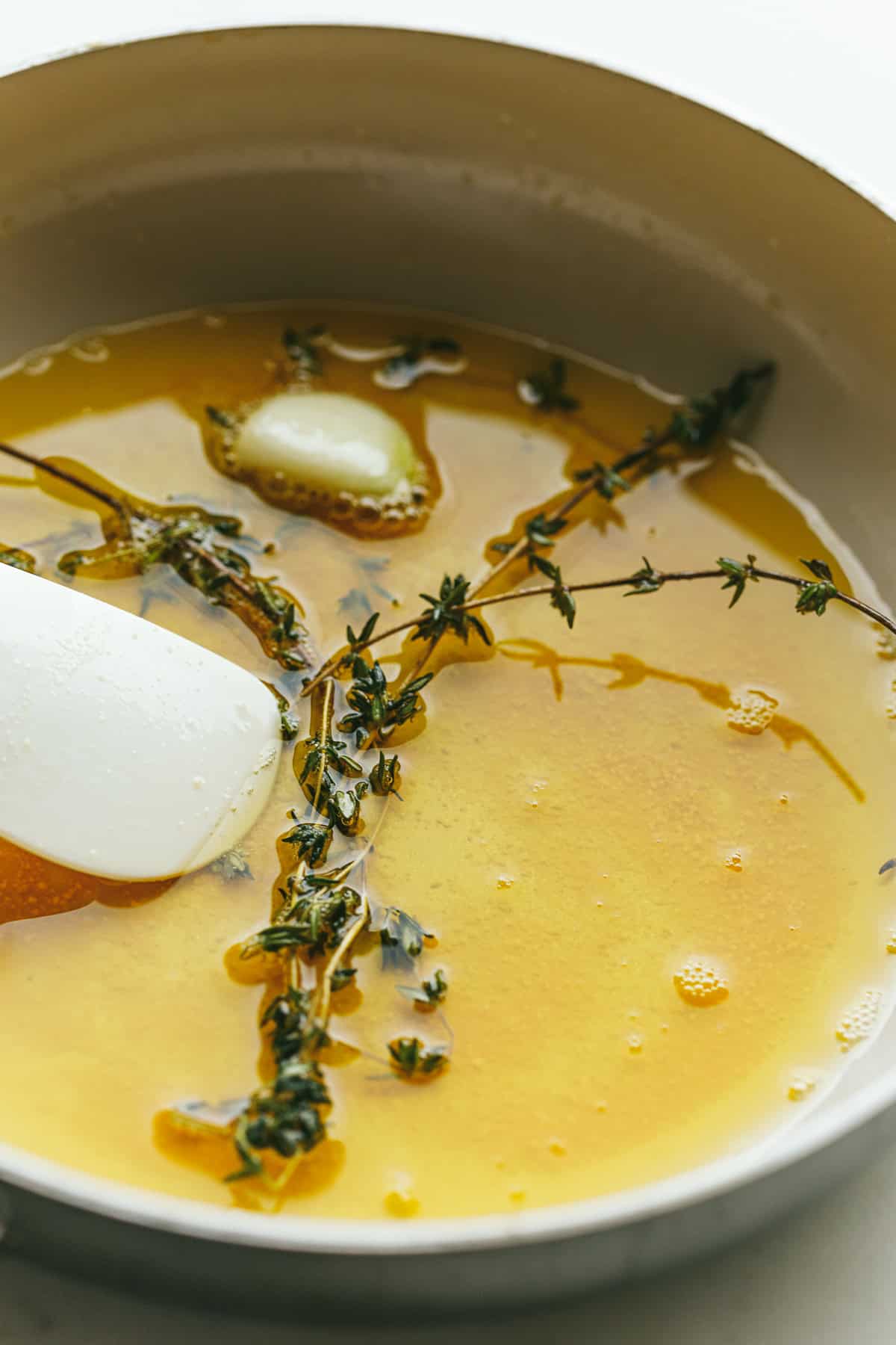 Cooking brown butter in a light colored pan with sprigs of thyme.