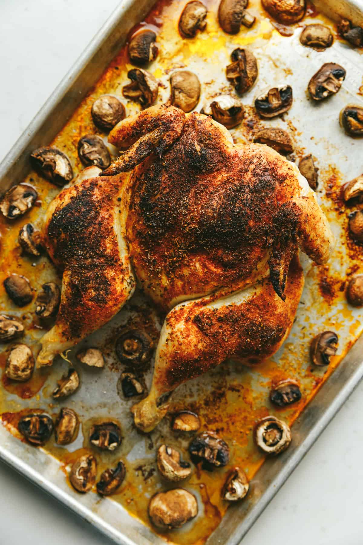 Spatchcock brown butter chicken and mushrooms on a sheet pan.