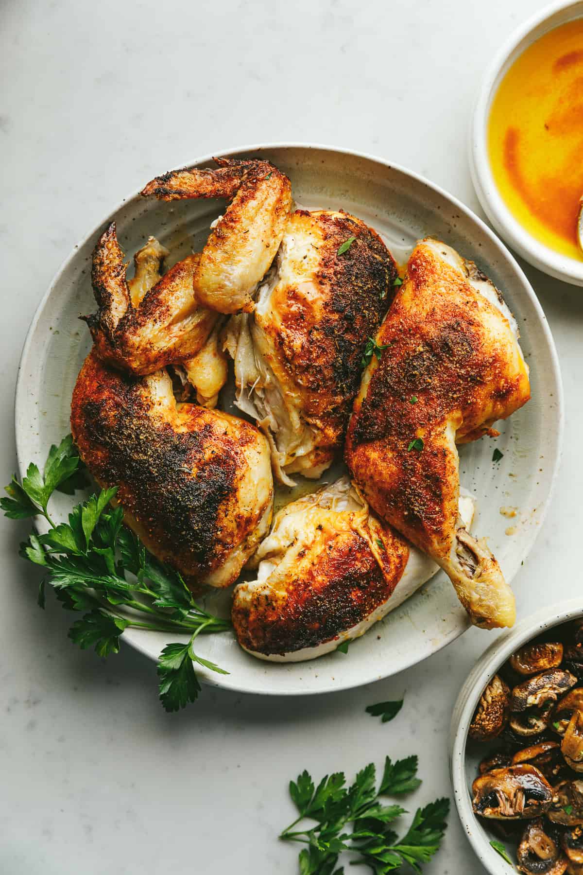 A plate with carved brown butter chicken and roasted mushrooms next to it.