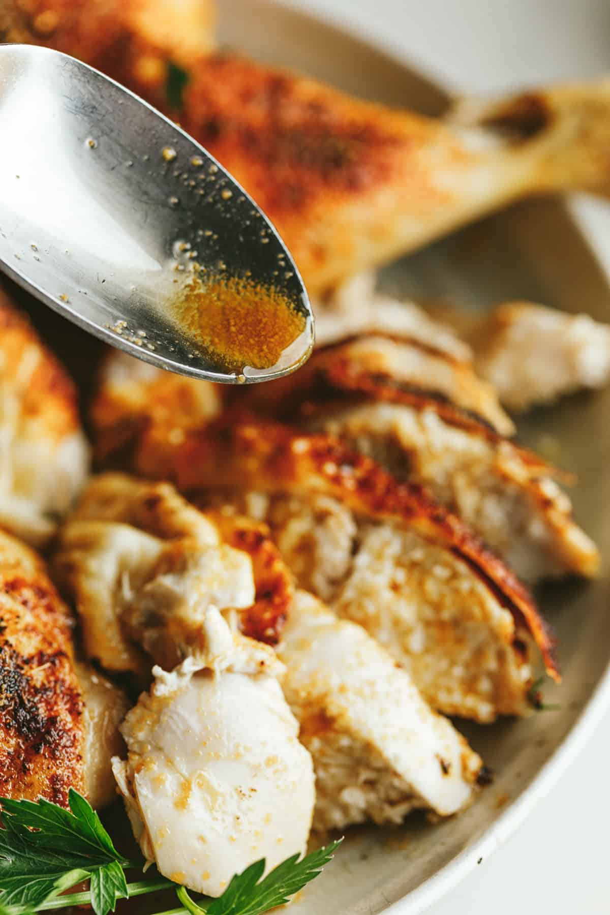 Pouring brown butter on top of roasted chicken.