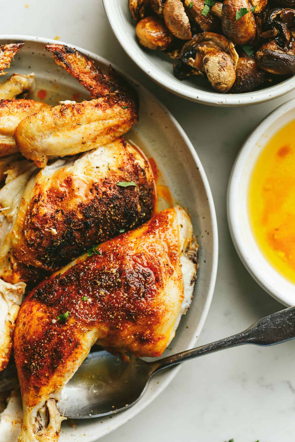 Brown butter chicken with roasted mushrooms in serving plates.