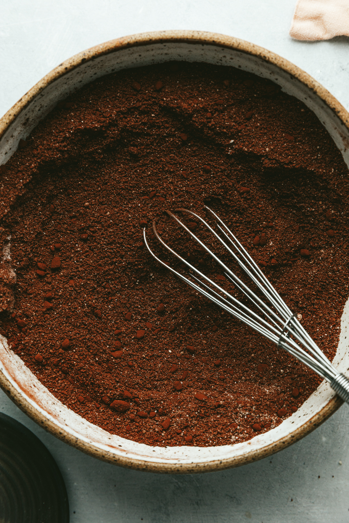 Dry ingredients for low-carb chocolate cake in a mixing bowl with a whisk.