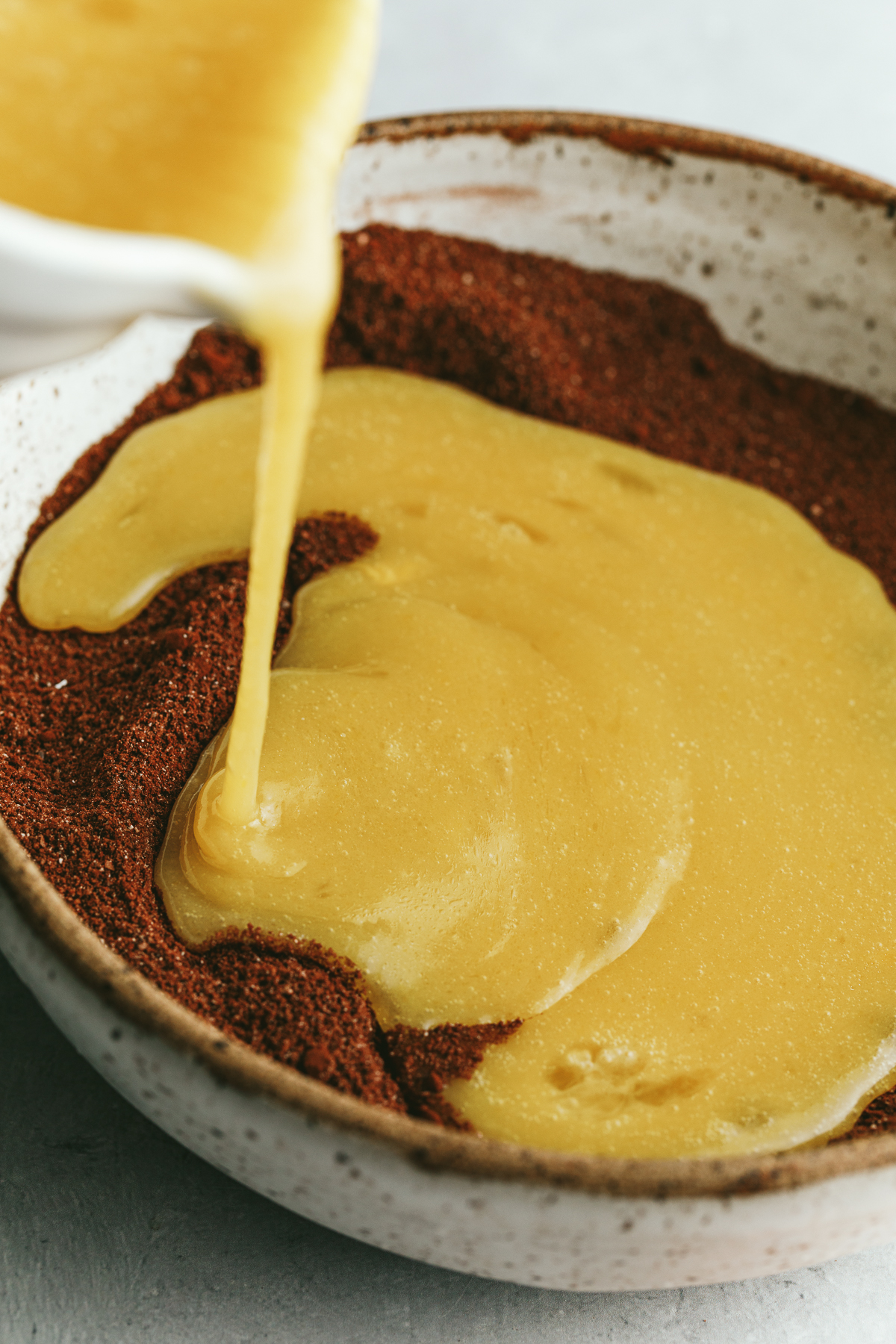 Pouring wet ingredients into a bowl for keto chocolate cake.