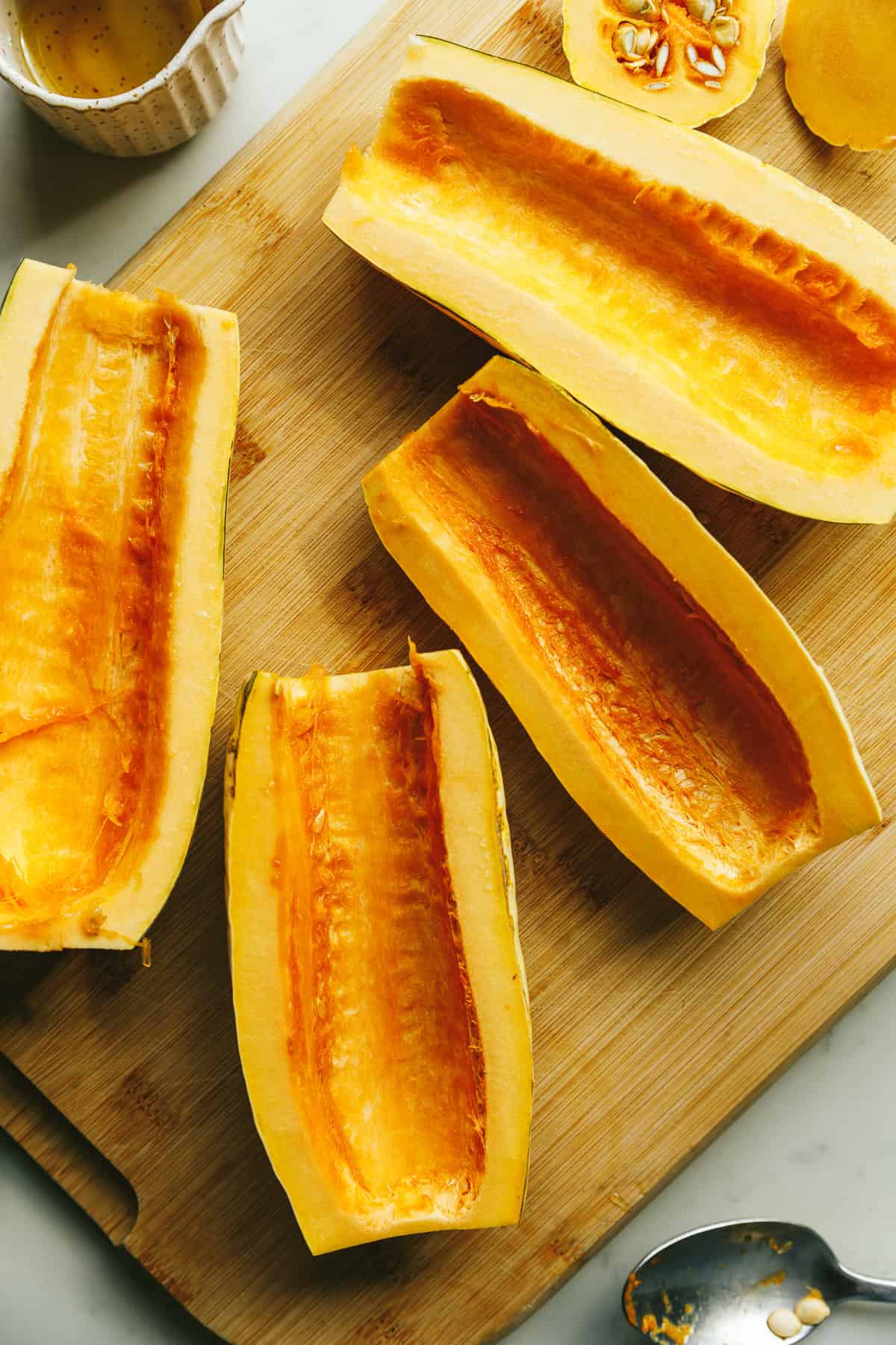 Halved butternut squash on a wooden cutting board.