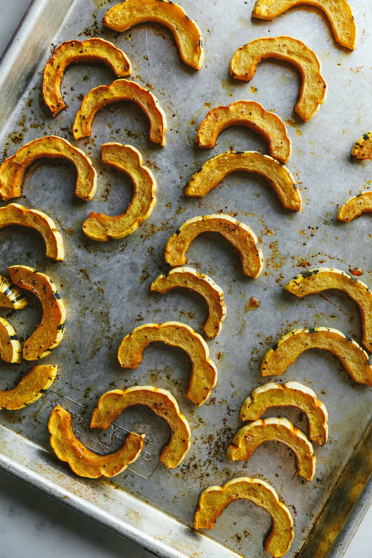 Delicata squash half-moons on a baking sheet.