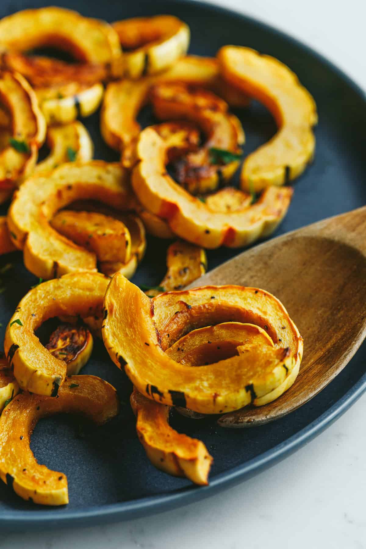 Roasted delicata squash with a wooden serving spoon.
