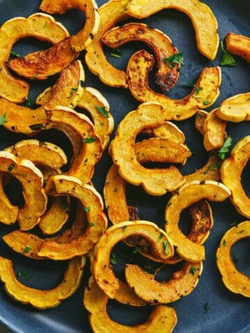 Roasted delicata squash with parsley on a blue plate.